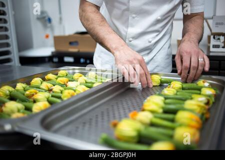 Courgette flowers stuffed with white cheese being layed out on a baking tray by a chef Stock Photo