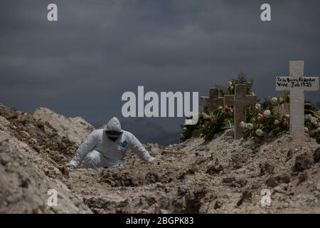 20 April 2020, Mexico, Tijuana: A man in a protective suit works between graves during a funeral in the context of the Covid 19 pandemic. Covid 19 victims are buried in the State Cemetery No. 13, in accordance with special measures. Relatives are only allowed to attend funerals at 50-meter intervals. Mexico has not imposed any exit restrictions, but has urged the population to stay at home if possible. The country has confirmed 9501 Covid-19 infected and 857 coronavirus deaths. Almost a new percentage of cases are recorded in the state of Baja California, which borders on the USA. Photo: Omar Stock Photo