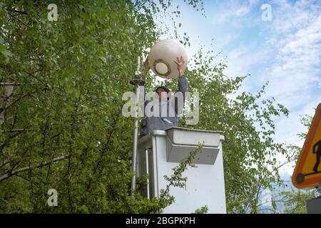 Worker in lift bucket repair street light. People change the lamp on a street lamp Stock Photo