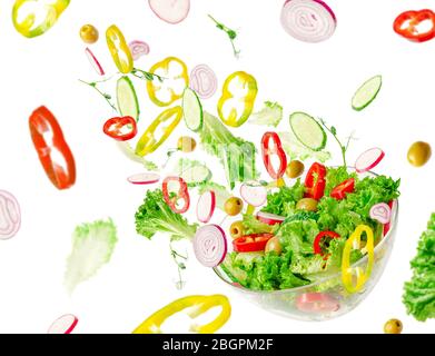 Flying vegetable salad ingredients over transparent bowl. Vitamins and healthy eating concept. Stock Photo