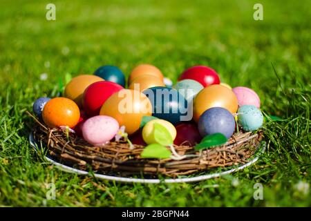 Stock photo of Easter eggs in a wooden basket on green grass as a symbol of the Easter in the Christian religion.