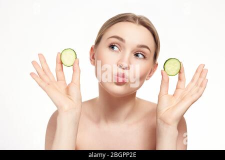 Beautiful young woman receiving facial mask of cucumber. Blonde woman. Isolated Stock Photo