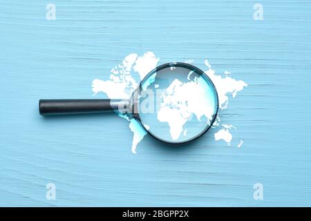 Abstract image of a world search with magnifier on a wooden background. Close up. Stock Photo