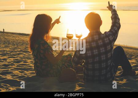 Couple celebration drinking red wine at sunset beach Stock Photo