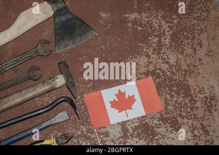 Labor Day in Canada, May 1. Lots of handy tools on old rusty background with Canada flag with copy space. Repair, workshop. Stock Photo