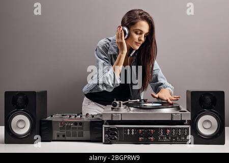 Young woman dj playing music on a gray background Stock Photo