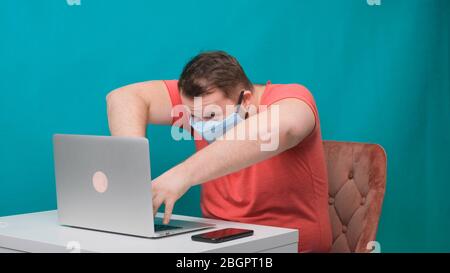 Funny frames of male using laptop. man working on a computer in a protective medical mask pretending to be a hacker. Stock Photo
