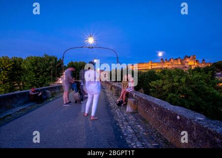 Tourists posing for pictures in front of the Chateau Comtal medieval castle from the Pont Vieux in Carcassonne, France, Europe Stock Photo