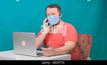 Man working from home. Using a smartphone. Bearded man in a protective mask works at home. Stock Photo