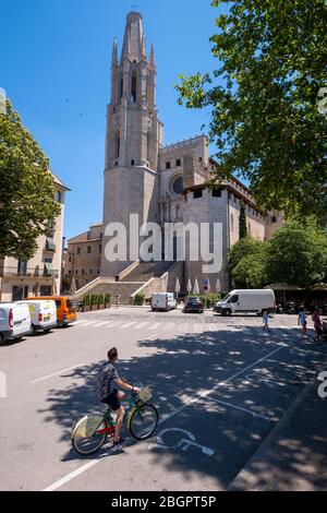 Tourist riding a bicycle in front of the Collegiate Church of Sant Felix aka Basílica de Sant Feliu in Girona, Catalonia, Spain, Europe