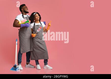 Cheerful African Couple Holding Cleaning Supplies And Pointing At Copy Space Stock Photo