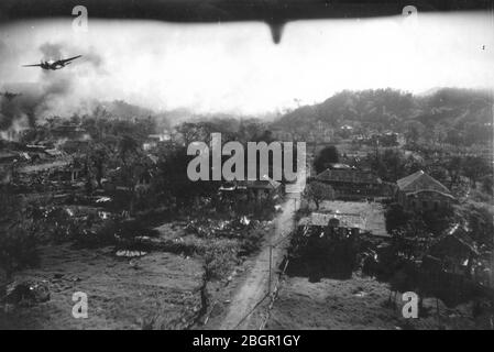 Bombs dropping # 1.  Army Air Force is flying bombing runs over the hilly town of San Fernando, the Philippines, c. 1945. The back-looking view under an airplane shares the air space with a medium bomber flying over San Fernando. That bomber has its bomb bay door open and heavy dust and smoke rise from several places on the ground where bombs have hit. The bomber seems to be either a Douglas A-20 Havoc medium bomber or a Douglas A-26 Invader medium bomber. To see my other WW II-related images, Search:  Prestor  vintage  WW II Stock Photo