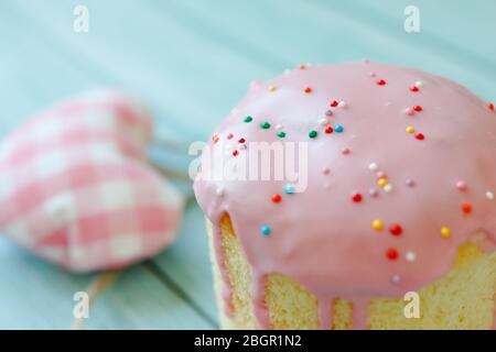 Sweet bread traditional easter orthodox celebration cake panettone also called kulich glazed with pink icing and raisins and three colored hearts on Stock Photo