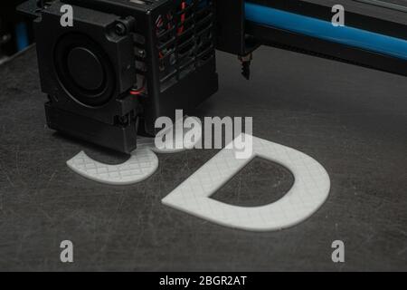 3D printer prints the word 3D with white filament PLA Stock Photo