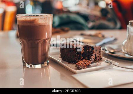Homemade chocolate brownie with nuts on plate with hot chocolate close up on wooden table Stock Photo