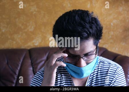 A sick man with a mask on his face sitting on sofa  Stock Photo