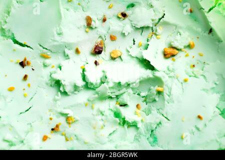 Close-up view of natural food background from homemade freshly cooked cold pistachio pastel green colored ice-cream dessert with ground-up nuts. Top v Stock Photo