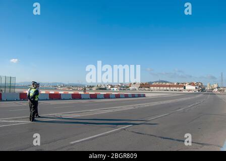 Police officers blocking the road crossing the runway of Gibraltar International Airport Stock Photo