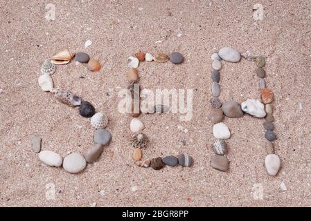 Word sea made from sea shells and stones on sand Stock Photo