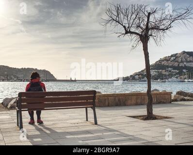 Dark heair woman traveler relax on bench on sea promenade. Stock Photo