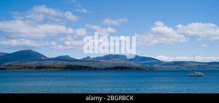 Moored yacht with Isle of Arran in distance viewed from Kintyre, Argyll coast, Scotland Stock Photo