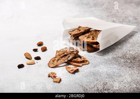Dried fruit bread made from wheat flour,  honey, walnuts, plums and grapes in a  breakfast paper bag. Homemade healthy food concept. Copy space. Stock Photo