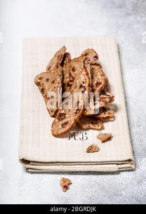 Sliced of dry fruit bread made from wheat, nuts, plums and grapes on a linen  kitchen towel. Homemade healthy food concept. Stock Photo