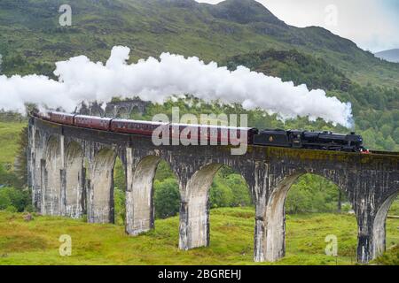 'The Jacobite' locomotive steam train on West Highland Rail crosses famous Glenfinnan Viaduct tourist spot in the Highlands of Scotland Stock Photo