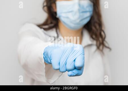 Stop SARSCoV, virus 2020, chinese virus COVID-19. Womens hand in blue medical gloves show fist. Concept of protection against HIV. Doctor in blue Stock Photo