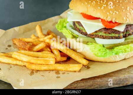 Burger vegetarian with spinach cutlet, vegetables and potato fries closeup, top view. Tasty light fast food. Enjoying healthy food. Stock Photo