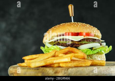 Tasty vegetarian burger with vegetables and spinach cutlet. Crispy potato fries on the wooden board. Nice view. Tasty light fast food. Stock Photo
