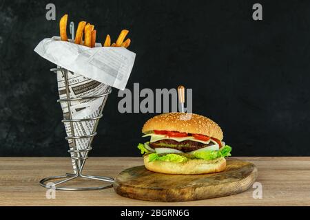 Vegetarian hamburger with spinach cutlet and vegetables. Crispy potato fries in eco paper bag. Wooden natural background, space for your text. Tasty l Stock Photo