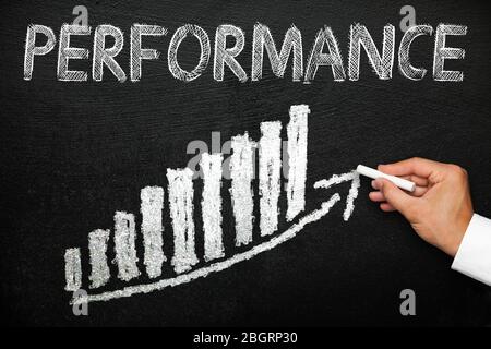 Blackboard with handwritten performance text. Arrow going upwards and stack chart. Performance and progress concept. Stock Photo