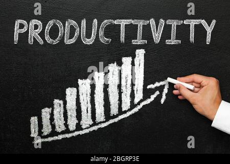 Blackboard with handwritten strategy text. Arrow going upwards and stack chart. Hand with chalk in hand. Direction and success concept. Stock Photo