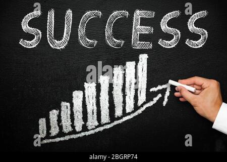 Blackboard with handwritten success text. Arrow going upwards and stack chart. Goal and progress concept. Stock Photo