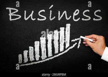 Blackboard with handwritten business text. Arrow going upwards and stack chart. Success and progress concept. Stock Photo