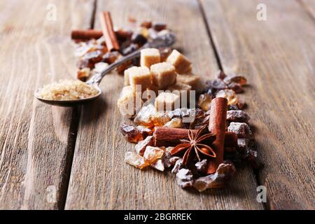 Brown sugar cubes, reed and crystal sugar, spices on wooden background Stock Photo