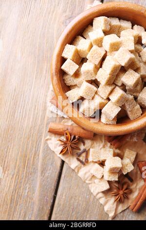 Brown sugar cubes in bowl, star anise and cinnamon sticks on wooden background Stock Photo