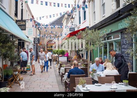 Locals and tourists in pavement cafes and artisan shops in Halkett Street by St Helier Central Market in Jersey, Channel Isles Stock Photo