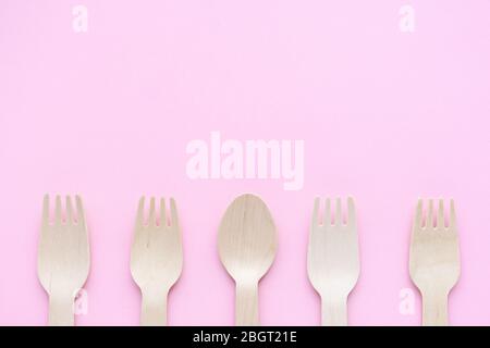 eco friendly disposable kitchenware utensils on pink background. wooden forks and spoons. ecology, zero waste concept. top view. flat lay. copyspace Stock Photo