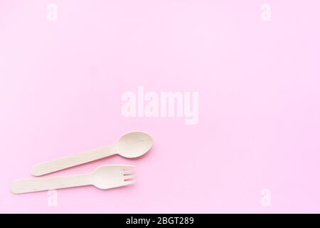 eco friendly disposable kitchenware utensils on pink background. wooden forks and spoons. ecology, zero waste concept. top view. flat lay. copyspace Stock Photo