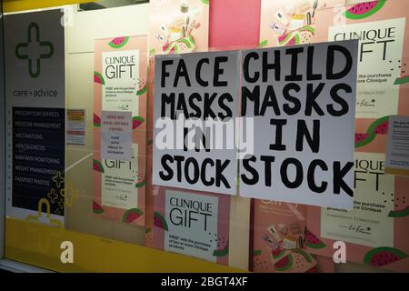 Adult and child face masks in stock hand written signs in a pharmacy window during the coronavirus covid-19 lockdown. Stock Photo