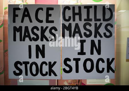 Adult and child face masks in stock hand written signs in a pharmacy window during the coronavirus covid-19 lockdown. Stock Photo