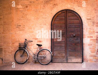 A bike parked near an old wooden door in the medieval town of Foligno, Umbria, Italy Stock Photo