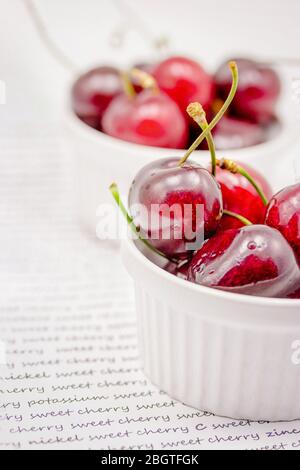 Bowls with red ripe sweet cherries with water drops on white background Stock Photo