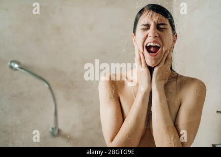 Woman relaxing at home in the hot shower ritual,singing in shower.Relaxing spa night in bathroom.Good personal hygiene routine.Skin,body care,aromathe Stock Photo