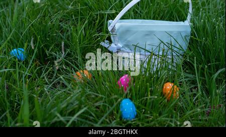 Multiple polka dotted Easter eggs surrounding a basket in the grass at sunset Stock Photo