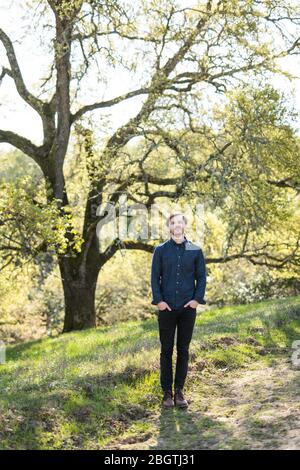 Full body portrait of man in casual clothes in front of Oak tree Stock Photo