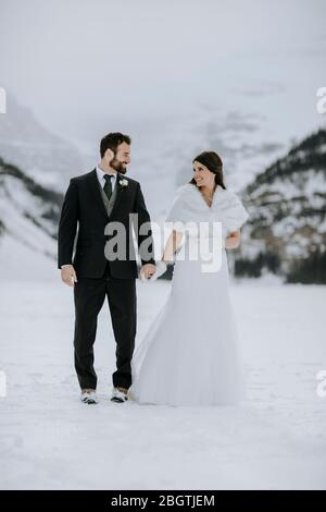 bride and groom in love on ice on frozen lake in mountains in winter Stock Photo