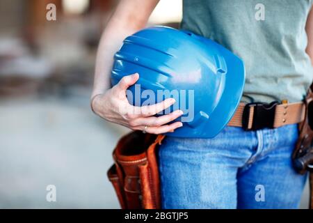 Close up of a female construction worker holding a hard hat Stock Photo